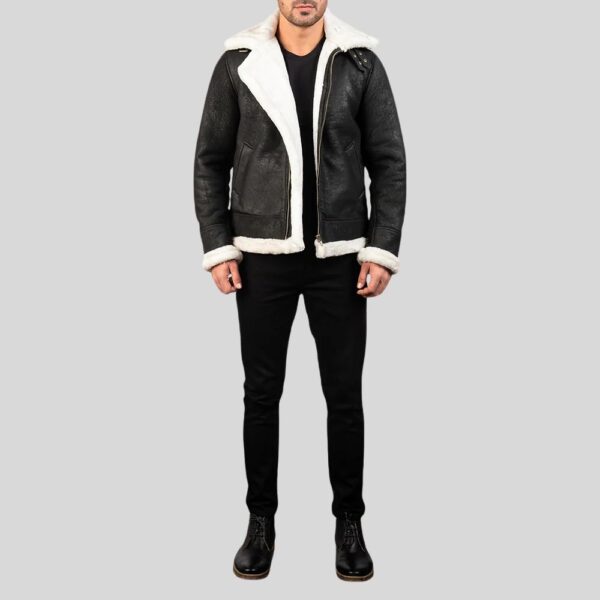 Ganzkörperansicht eines Mannes mit schwarzer Shearling Jacke mit weißem Lammfellkragen und schwarzen Schnürstiefeln