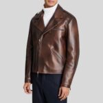 Halbseitige Frontansicht eines Mannes in brauner Glattlederjacke mit Reverskragen und schrägem Reißverschluss, kombiniert mit weißem Rollkragenpullover