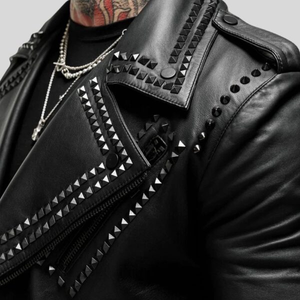 Makroaufnahme einer schwarzen Leder-Bikerjacke mit spitzen Nieten entlang Revers, Schulterriegel und Nähten – kombiniert mit Silberschmuck