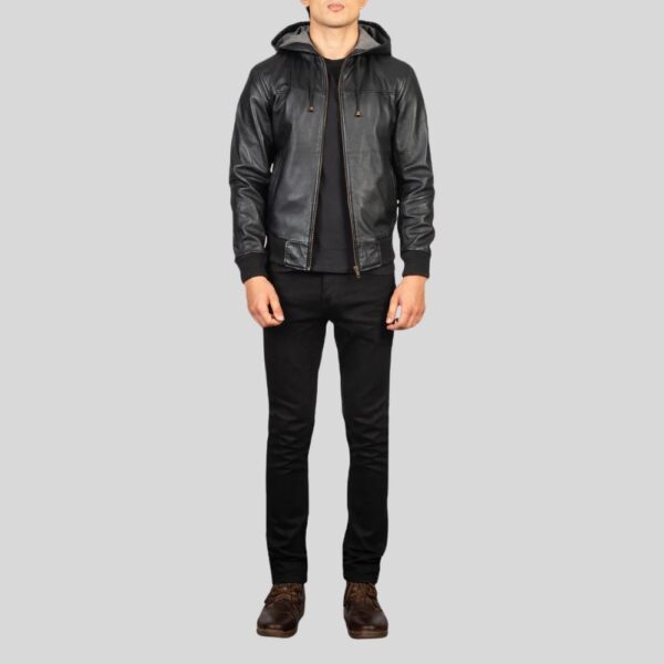Mann trägt schwarze Lederjacke mit Kapuze in kompletter Frontalansicht – schwarze Jeans und braune Schuhe