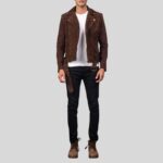 Modell trägt braune Wildleder-Bikerjacke mit Gürtel und asymmetrischem Reißverschluss, kombiniert mit weißem T-Shirt und schwarzer Hose