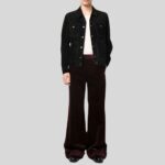 Modell trägt schwarze Wildlederjacke mit weißen Knöpfen, kombiniert mit bordeauxroter Schlaghose und weißen T-Shirt