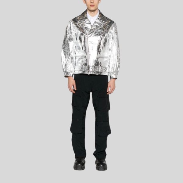 Modell trägt silberne Bikerjacke aus Metallic-Leder mit Gürtel und Reißverschluss, kombiniert mit schwarzer Cargo-Hose