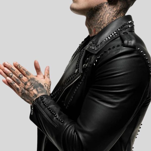 Nahaufnahme einer schwarzen Nieten-Bikerjacke mit sichtbaren Arm- und Hals-Tattoos – Detailansicht von Schulter und Revers