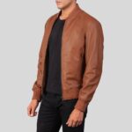 Seitenansicht einer cognacfarbenen Leder-Bomberjacke für Herren mit schwarzen Jeans und schwarzem Shirt