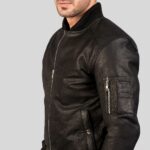 Seitenansicht einer schwarzen Leder Bomberjacke für Herren mit Zipper-Ärmeltasche und Druckknopftasche