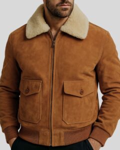 Nahaufnahme einer Wildlederjacke für Herren mit cremefarbenem Shearling-Kragen, Knopftaschen und elastischem Saum