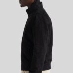 Mann trägt schwarze Wildleder Bomberjacke mit Stehkragen, Reißverschluss und Rippbündchen – elegante Vorderansicht