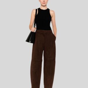 Frau trägt eine braune Wildlederhose in modernem Schnitt, kombiniert mit schwarzem ärmellosen Top, Umhängetasche und Stiefeletten