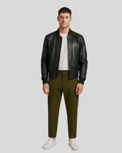 Herren Olivgrün Suede Hose kombiniert mit schwarzer Lederjacke, weißem Shirt und Sneakern für einen modernen Freizeit-Look