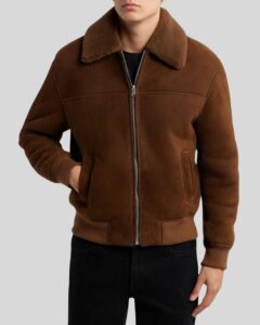 Herren trägt braune Suede Bomberjacke mit Reißverschluss, Shearling-Kragen und Rippbündchen – Hände in Seitentaschen
