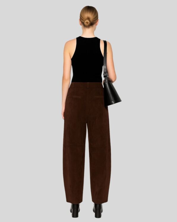 Rückansicht einer Frau in brauner Wildlederhose mit modernem Schnitt, kombiniert mit schwarzem Top, Schultertasche und Absatzstiefeletten