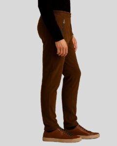 Seitenansicht eines Mannes in brauner Herren Wildleder Joggerhose mit elastischem Bund und Zipper-Taschen, kombiniert mit schwarzen Pullover und Sneakers